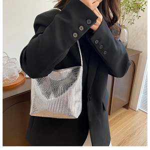 Close-up of a silver crocodile pattern handbag worn by a model in a black blazer