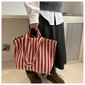 Detail of red and white striped canvas tote bag with dual handles for shoulder or hand carry