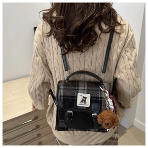 Detail of vintage plaid backpack with leather trim and brown plush puppy charm