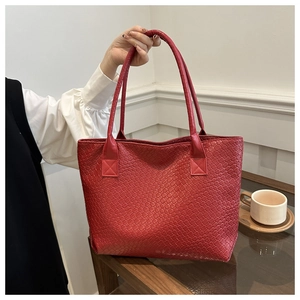 Close-up of red woven leather tote bag texture and long shoulder straps in a home setting