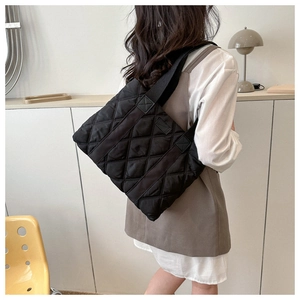 Rear view of a model wearing the black quilted nylon tote bag with rhombus pattern