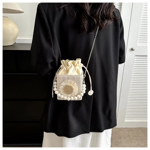 Detail of woven straw bucket bag with sunflower decor and elegant pearl top handle