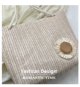 Detail of woven straw tote bag with daisy floral accent and cotton rope handles