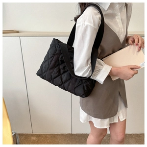 Side view of a black quilted tote bag showing large capacity on a model for daily commute