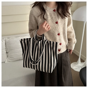 Detail of black and white striped canvas tote bag showing dual straps in a lifestyle setting