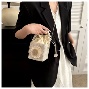 Detail of woven bucket bag with pearl handle and sunflower applique on a model