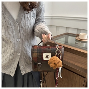 Detail of plaid wool backpack with leather trim and cute brown poodle plush charm