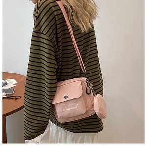Detailed shot of pink nylon crossbody bag with small round coin purse accessory