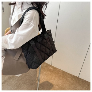 Side view of black quilted nylon tote bag featuring diamond patterns and wide shoulder strap