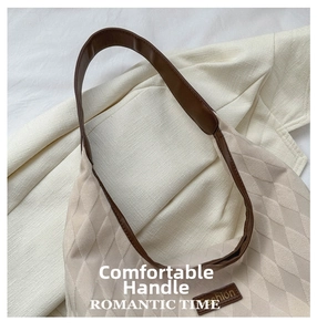 Close-up of quilted beige tote bag with brown leather handles and fashion logo detail