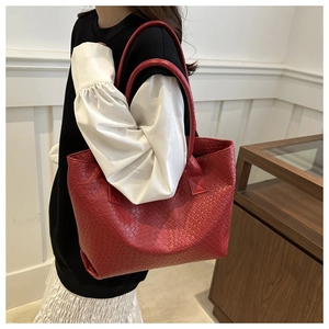 Detailed close-up of large red woven leather tote bag with premium texture and handle
