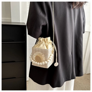 Detail of straw woven bucket bag with sunflower accent, pearl handle and chain strap