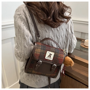 Detail of British style plaid backpack with plush bear charm and vintage leather straps