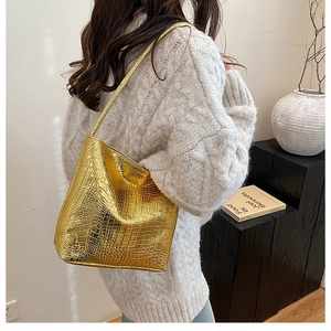 Golden crocodile pattern shoulder bag shown with lifestyle decor and metal luster