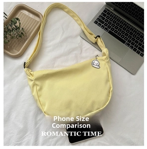 Light yellow crescent canvas bag next to a smartphone showing size comparison