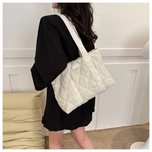 Quilted off-white oxford tote bag featuring a diamond pattern shown on a model shoulder