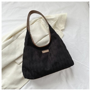 Detail view of black quilted tote bag with brown fashion patch and stylish shoulder strap