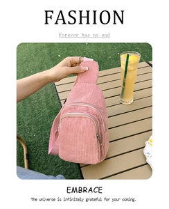 Close-up of pink corduroy waist bag with zippers on a wooden table in a garden setting