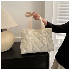 Detail of beige quilted oxford tote bag showing classic diamond lattice and handle strap