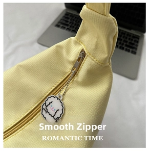 Detail of yellow checkered fabric bag with smooth metal zipper and cute lamb pendant
