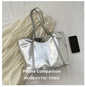 Silver metallic tote bag size comparison with a smartphone on white fabric background
