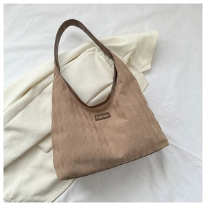 Macro shot of rhombus quilted texture and brown leather label on khaki hobo shoulder bag