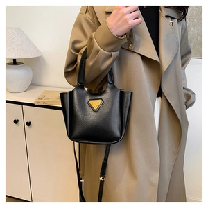 Detail of a black matte bucket bag with a yellow triangle logo and slim shoulder strap