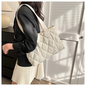 Detail of beige quilted tote bag with diamond stitching shown on a model