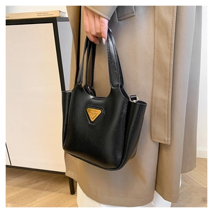 Close-up of black leather bucket bag with oily texture and gold triangle logo