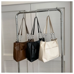 Close-up of stylish tote bags in brown, black, and beige with metal chain straps