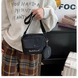 Detail of black nylon crossbody bag with mini round pouch and white dachshund lettering