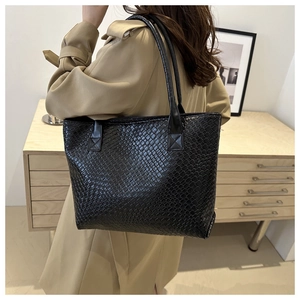 Close-up of black woven texture tote bag worn with a stylish khaki trench coat