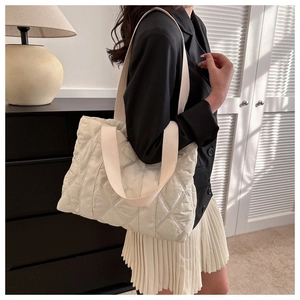 Detail of cream quilted tote bag featuring classic diamond stitching and wide strap
