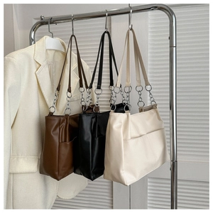Detailed view of tote bags in brown, black, and beige with metal chain straps
