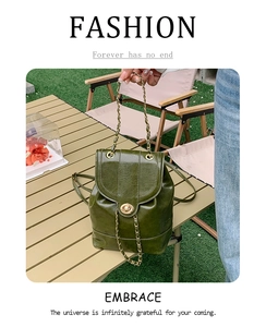 Close-up of vintage dark green oil wax leather backpack with chain strap on wooden table