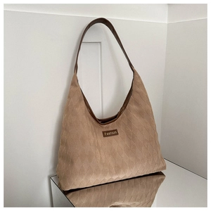 Macro detail of quilted khaki suede tote bag with brown leather strap and fashion label