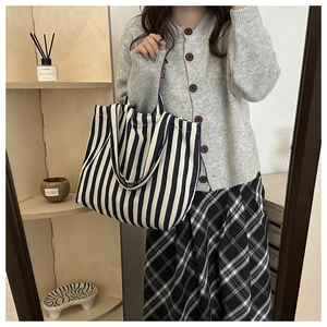 Detail of large canvas tote bag with vertical stripes shown in a lifestyle home setting