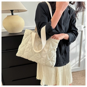 Detail of beige quilted nylon tote bag with rhombic stitching and wide shoulder strap
