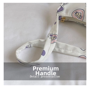 Detail showing white waterproof shoulder bag with purple dots and LUCK heart pattern