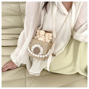 Straw crossbody bag featuring pearl handle and floral sunflower detail shown on model
