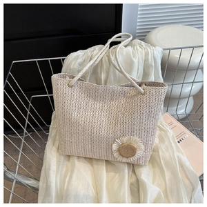 Detail of woven straw tote bag featuring a decorative sunflower and rope handle