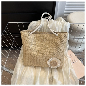 Close-up of woven straw tote bag with a white daisy applique and cotton rope handles