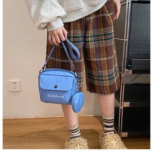 Detail of light blue nylon crossbody bag with matching round coin purse and white text