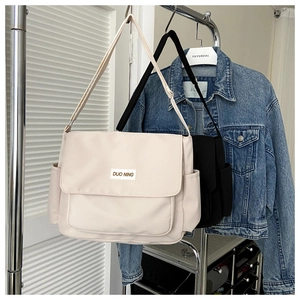 Detailed view of large canvas messenger bags in beige and black with adjustable straps