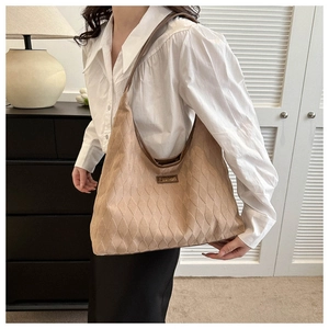 Detail of light brown quilted tote bag with soft velvet texture and metal Fashion badge