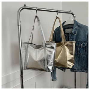 Detailed view of silver and gold metallic tote bags hanging on a rack with a denim jacket