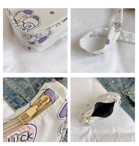 Detail of white cartoon shoulder bag featuring purple luck pattern and metal zipper closure