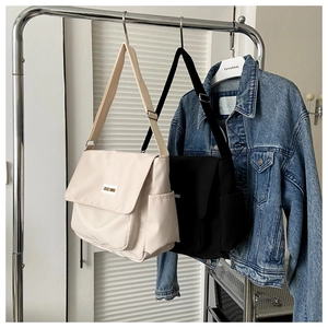 Detail view of canvas messenger bags in black and beige with adjustable wide straps