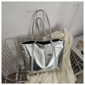 Detail of silver metallic tote bag with slender handles inside a metal basket