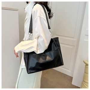 Detail of black PU leather tote bag with silver chain straps and large front pocket
